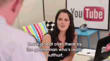 a woman is talking to a man in front of a youtube sign