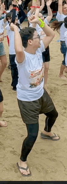 a man is dancing on the beach with a group of people behind him .