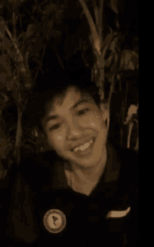 a young man is smiling and looking at the camera while wearing a black shirt .