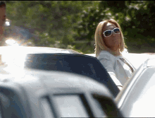 a woman wearing sunglasses is sitting in the back of a car