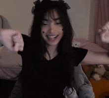 a girl with long dark hair is wearing a black shirt and a headband with a bow on it .