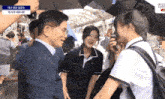 a man in a suit is talking to two girls under an umbrella with a caption that says ' seoul '