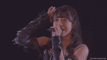 a woman singing into a microphone with a watermark that says cup front international
