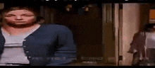 a woman in a blue cardigan is standing in front of a door .