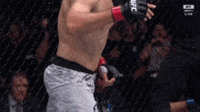 a man wearing a pair of ufc gloves is standing in a boxing ring