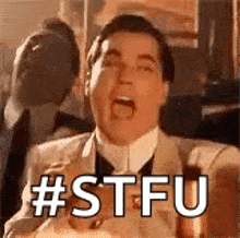 a man in a suit and tie is making a funny face with his mouth open and the words `` stfu '' written on it .