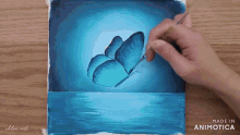 a person is painting a blue butterfly on a wooden surface