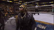 a man in a wrestling ring with a aew banner in the background