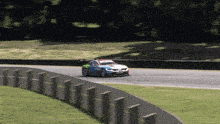 a blue and green race car is driving down a road