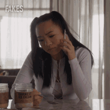 a woman sitting at a table with a jar of fakes ice cream