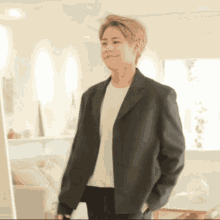 a man wearing a black jacket and white shirt is standing in a living room