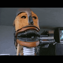 a wooden mask with a hose attached to it sits in front of a vcr and a tv