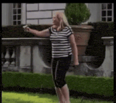 a woman in a striped shirt is standing in front of a house