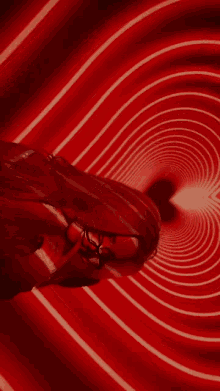 a woman wearing glasses is laying in a red tunnel .