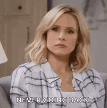a woman in a plaid shirt is sitting on a couch and saying `` never going back . ''