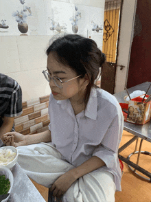 a woman wearing glasses is sitting at a table with food