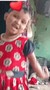 a little girl in a red dress with a heart on her head is dancing .