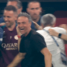 a man wearing a qatar shirt is laughing with another man