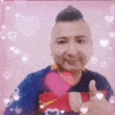 a man with a mohawk is giving a thumbs up in front of a pink background .