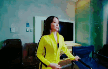 a woman in a yellow jacket is standing in a room