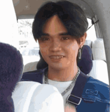 a young man is sitting in the back seat of a car and smiling at the camera .
