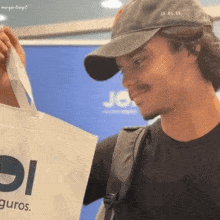 a man wearing a hat holds a bag that says seguros