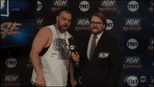 two men in front of a wall that says aew