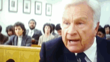 a man in a suit and tie is giving a speech in front of a crowd