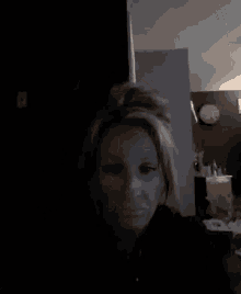 a woman in a dark room with a clock hanging on the wall