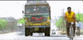 a man in a yellow shirt is riding a bicycle in front of a truck