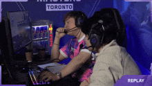 two people playing a video game in front of a sign that says " replay "