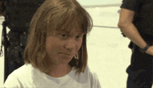 a woman in a white shirt stands in front of a man in a black shirt