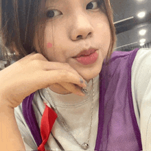 a close up of a woman wearing a purple vest and necklace