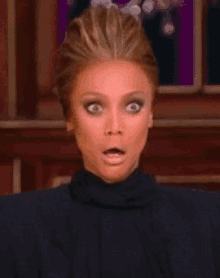 a woman with a surprised look on her face is wearing a black shirt .