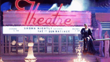 a woman stands in front of a theatre sign that says shown nightly sat and sun matinee