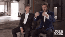 two men in suits are sitting next to each other with the words fashion rocks in the corner