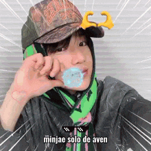 a person wearing a camo hat and a green scarf with the words minjae solo de aven on the bottom