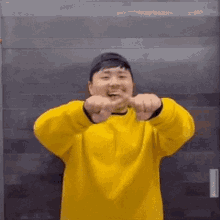 a man wearing a yellow sweater and a black hat is making a funny face .