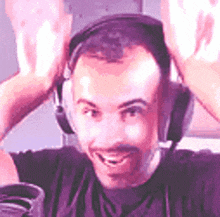 a man wearing headphones is sitting in front of a microphone and smiling .