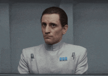 a man wearing a white uniform has a blue badge on his chest