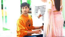a man wearing a los angeles sweatshirt is sitting next to a woman in a pink dress .