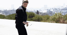 a man in a black jacket and black pants is standing on the side of a road