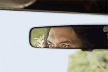 a man is looking through a rear view mirror of a car .