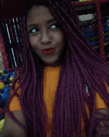 a girl with purple braids is wearing a yellow shirt and red lipstick