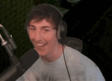 a young man wearing headphones is sitting in front of a microphone .