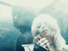 a woman is smoking a cigarette in front of a man