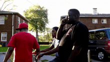 a man in a red shirt talks on a cell phone with two other men