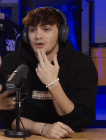a man wearing headphones and a black supreme hoodie