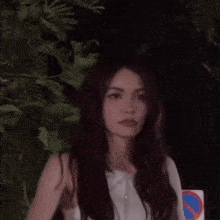 a young woman is standing in front of a no parking sign .
