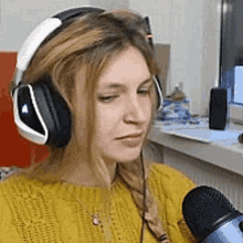 a woman wearing headphones is sitting in front of a microphone .